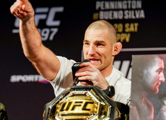 Sean Strickland com o dedo em riste ao lado do cinturão na coletiva do UFC 297