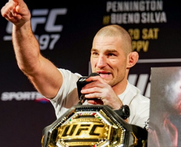 Sean Strickland com o dedo em riste ao lado do cinturão na coletiva do UFC 297